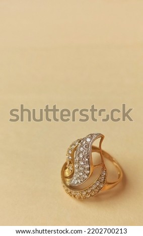 Gorgeous big ring in solid gold decorated with three leaves studded with small stones. beige background.profile picture.