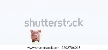 A pink piggy bank is placed on the table. The concept for financial, business, banking, save, loan, invest, budget, account, nobody, no people. Copy space on right for design or text white background.
