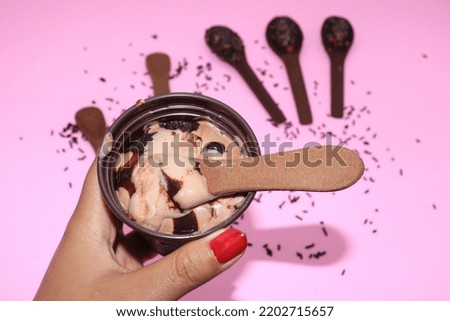 ice cream bowl for dessert, ice cream scoop, hand with ice cream bowl, pink background,chocolate ice cream