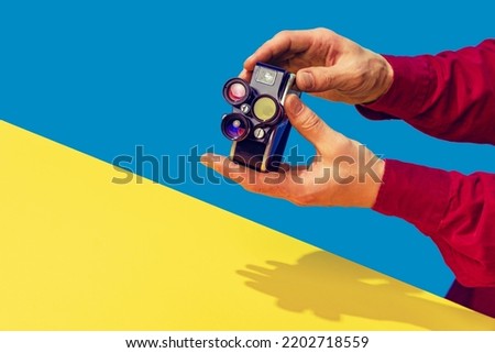 Pop art photography. Colorful image of retro photo camera on bright yellow tablecloth isolated over blue background. Concept of art culture, vintage things, mix old and modernity. Copy space for ad Royalty-Free Stock Photo #2202718559