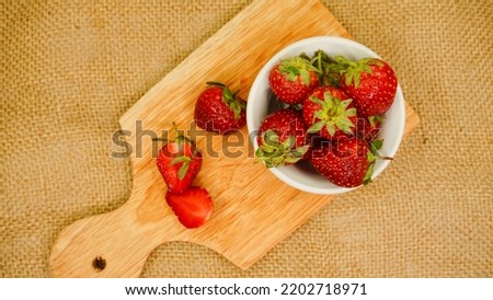 Fresh strawberries in glass bowl flat lay on cutting board. Healthy food on burlap mock up. Delicious, sweet, juicy and ripe berry background with copy space for text