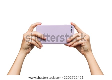 Mobile phone with photo camera in a lilac case in female hands isolated on a white background. Blank with an empty copy space for the design. Mockup of a smartphone. A young woman takes picture