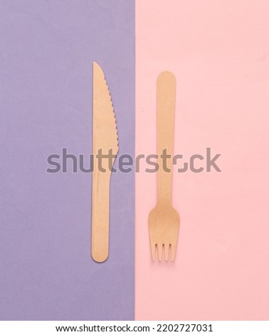 Wooden knife and fork on purple pink background. Eco products