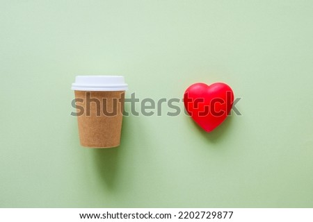 Paper eco-friendly cup and red heart on a green background. The concept of protecting nature.