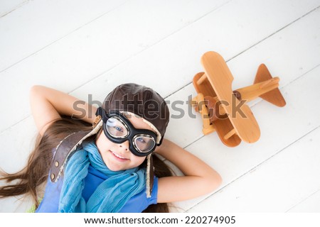Happy kid playing with toy airplane. Kid lying on wooden floor at home