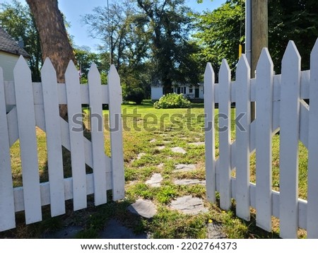 A white picket fence that is open a little on both sides. Royalty-Free Stock Photo #2202764373