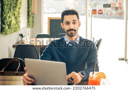 Portrait of young businessman with laptop at cafe shop
