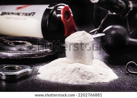 spoon with Creatine, whey or casein, whey supplements, protein bar for physical exercises, gym in the background, muscle mass gain Royalty-Free Stock Photo #2202766881