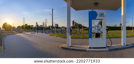 Hydrogen fuel pump for automobiles running on pollution-free hydrogen-powered fuel cells. Self service hydrogen filling station with oil refinery on the background Royalty-Free Stock Photo #2202771933