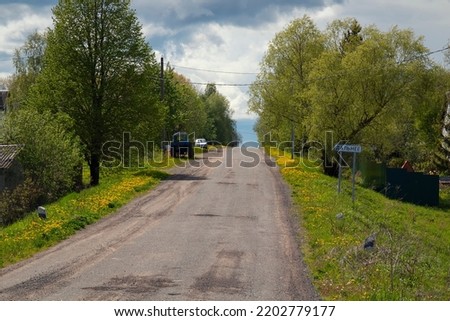 Translate:Dalneye. A country road, a road sign and a agrimotor by summer day