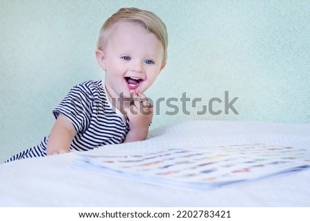 Defocused smiling child reading a picture book in bed at home.Copy space - concept of preschool family education, leisure, development, intelligence, interest, skills, alphabet learning, entertainment