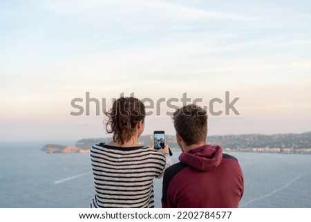 couple sitting with their backs to each other taking a picture with their cell phone with copy space