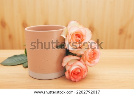 Pink cup of drink with rose flowers - vintage card with wooden background with copy space