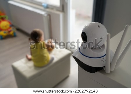 Surveillance camera baby monitor at home monitoring small child while playing in room childhood family protection parenthood concept Royalty-Free Stock Photo #2202792143