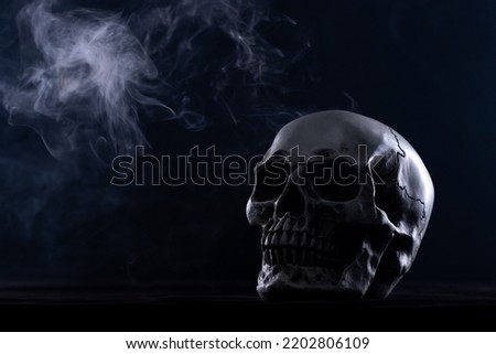 Halloween human skull on an old wooden table over black background. Shape of skull bone for Death head on halloween festival which show horror evil tooth fear and scary with fog smoke, copy space