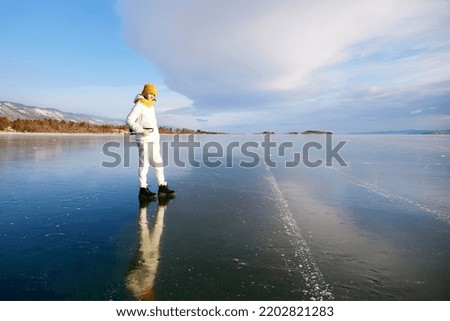 Portrait of a smiling athlete with figure skates on a frozen lake Baikal on a sunny winter day. Active recreation, unity with nature, outdoor sports, natural background.