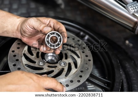 Mechanic check and replace Motorcycle wheel bearings , working in garage . repair and  maintenance motorcycle concept .selective focus Royalty-Free Stock Photo #2202838711