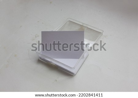 A set of blank business name card in transparent acrylic box with the standing one, is isolated on white textured desk background for corporate identity mockup or aesthetics stylish presentation.