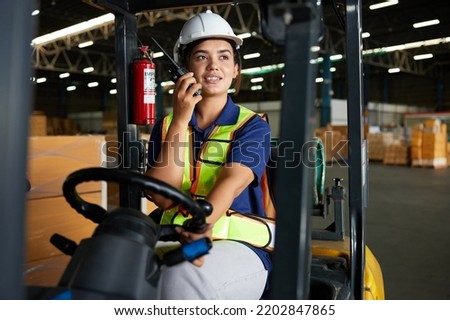 Indian worker driving a forklift and using walkie talkie in warehouse storage Royalty-Free Stock Photo #2202847865