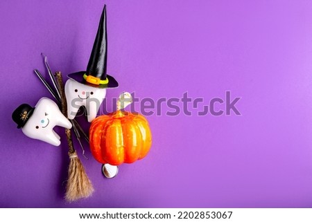 dental concept. figurines of teeth in halloween costumes and dental tools. pumpkins and a broom.on a purple background