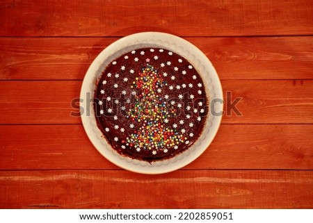 Cake. chocolate cake decorated with a Christmas tree and white snowflakes. on a white plate. a cake on a wooden background. The concept of Christmas and New Year. view from above.close-up
