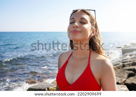 Happy beautiful carefree woman breathing fresh air enjoying wind on the beach. Relaxed bikini woman with closed eyes feeling good and free outdoor.