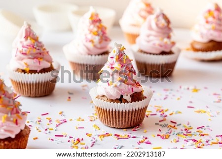 Frosted homemade carrot cupcakes with colorful birthday sprinkle close-up, horizontal image
