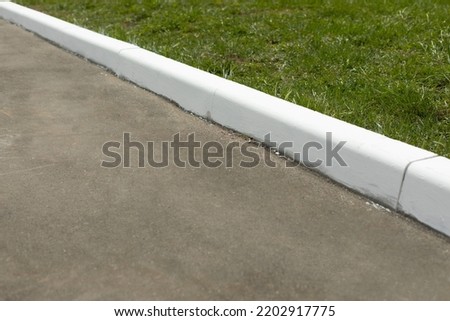 Painted curb. White curb on road. Landscaping in city. White paint.