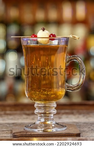 Non-alcoholic mulled wine, garnished with apple, with spices in a glass stands against the backdrop of a bar in a restaurant or in a pub. Space for text design
