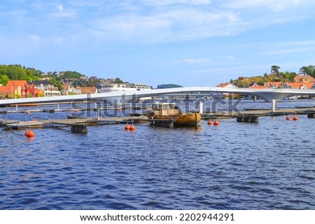 A wooden boat in the guest marina in Mandal with the white bridge, a Footbridge in background, Norway Royalty-Free Stock Photo #2202944291