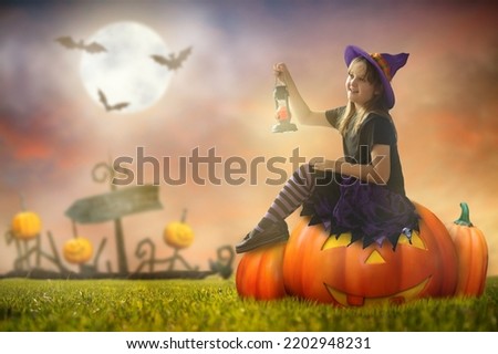 Little witch sitting on giant pumpkin lantern on Halloween night. Huge full moon and bats in the background. Kids trick or treat costume. Children have fun. Spooky and scary celebration. 