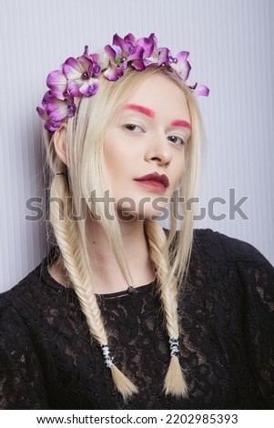 Fashion model woman posing in studio. Portrait of beautiful female. Art design fashion make up. Female model posing with flowers in her hair, looking at the camera