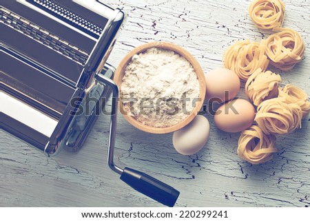 tagliatelle,eggs and pasta machine on old table