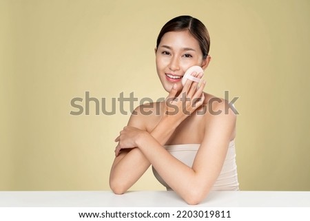 Ardent woman applying her cheek with dry powder and looking at camera. Portrait of younger with perfect makeup and healthy skin concept.