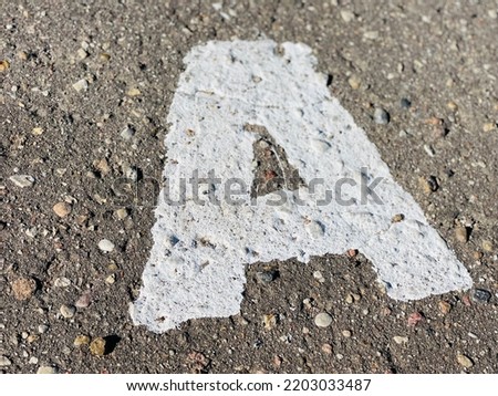 Stencil alphabet letters paint on asphalt road.