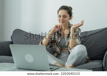 Front view of a girl at a laptop holding a phone in her hands. Communication online. Modern work. Green screen. Generation Z. Millennials