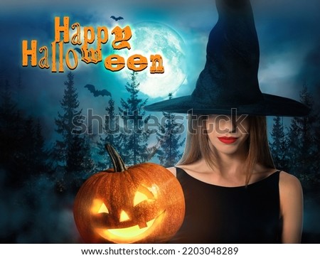 Happy Halloween. Woman wearing witch hat with spooky pumpkin jack o'lantern in misty forest under full moon