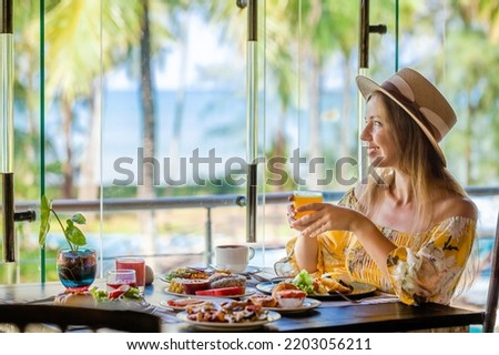 Tropical vacation. Breakfast in modern hotel resort with sea and palm trees on background. Traveler woman on summer holidays on Phuket, Thailand. Exotic travel in Southeast Asia Royalty-Free Stock Photo #2203056211