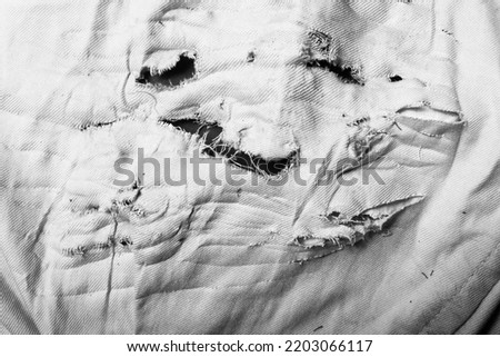 Close-up black and white texture photo of torn, burned and damaged cloth. Royalty-Free Stock Photo #2203066117