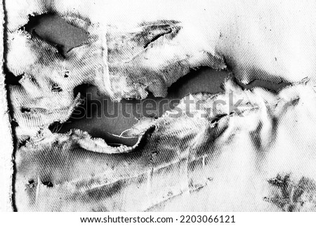 Close-up black and white texture photo of torn, burned and damaged cloth. Royalty-Free Stock Photo #2203066121