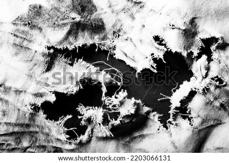 Close-up black and white texture photo of torn, burned and damaged cloth. Royalty-Free Stock Photo #2203066131