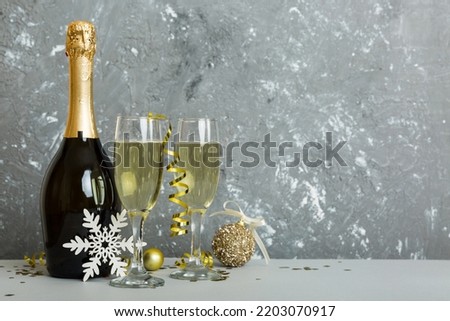 Champagne bottle with confetti, glasses and christmas decor on colored holiday background. Flat lay New Year decorations.