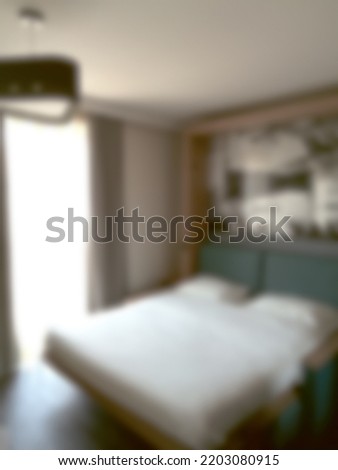 Blurred background of a room with a euro bed, a picture on the wall, daylight from the window