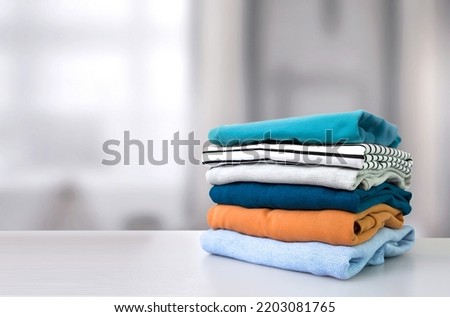 Stack of colorful clothes. Pile of clothing on table empty space background. Laundry and household. Royalty-Free Stock Photo #2203081765