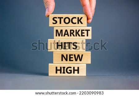 Stock market hits new high symbol. Concept words Stock market hits new high on wooden blocks on a beautiful grey background. Businessman hand. Business stock market hits new high concept. Copy space.