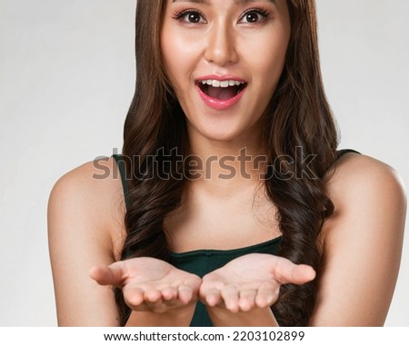 Closeup portrait of ardent woman looking at camera, holding empty space for product, advertising text place, isolated background. Concept of healthcare advertising for skincare, beauty care product.