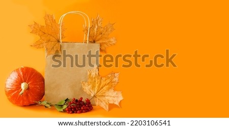 Banner on orange background ecological paper bag for seasonal and holiday shopping.  The concept of autumn sales, discounts for the Halloween holiday.  Space for copy text.  Front view.