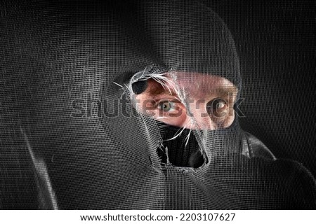A peeping tom looking through a torn window screen in a creepy moment. Royalty-Free Stock Photo #2203107627