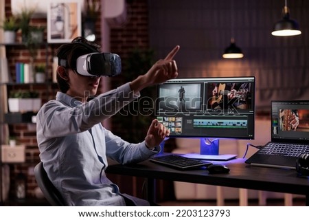 Film maker editing movie montage with virtual reality glasses, using multimedia production software to create footage. Edit video with color grading and visual effects, working with vr goggles. Royalty-Free Stock Photo #2203123793