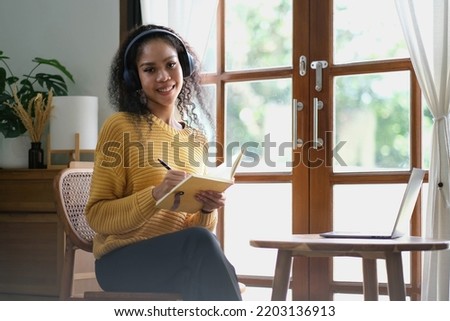 Smiling Asian young female using headset looking at laptop screen listen and learning online courses. Happy asian business woman with headphones video call for customer service.
